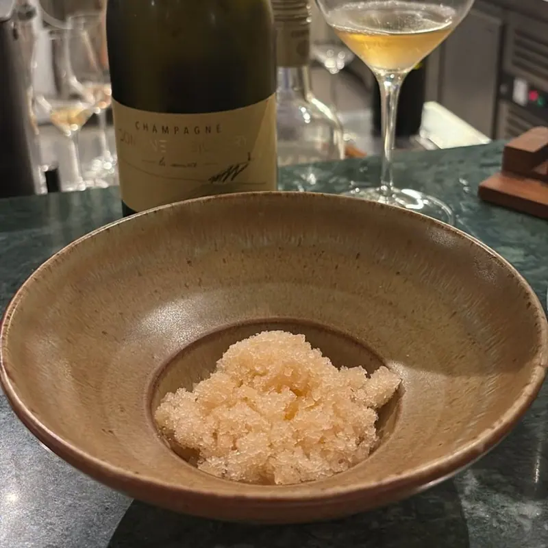 Pink granita in a bowl, next to a bottle of champagne