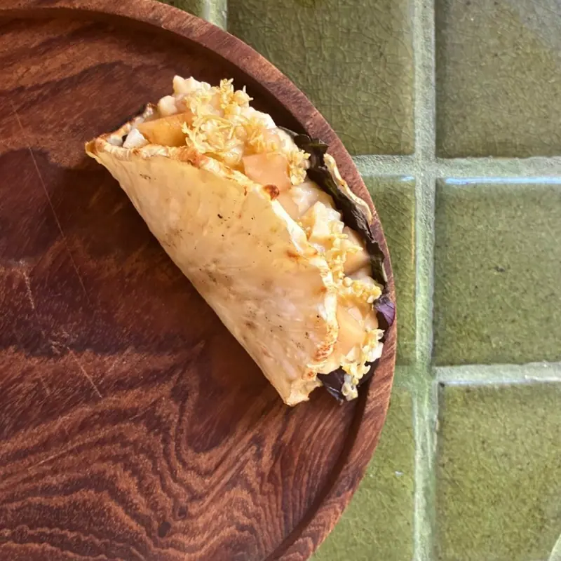 A folded, filled flatbread on a wooden plate