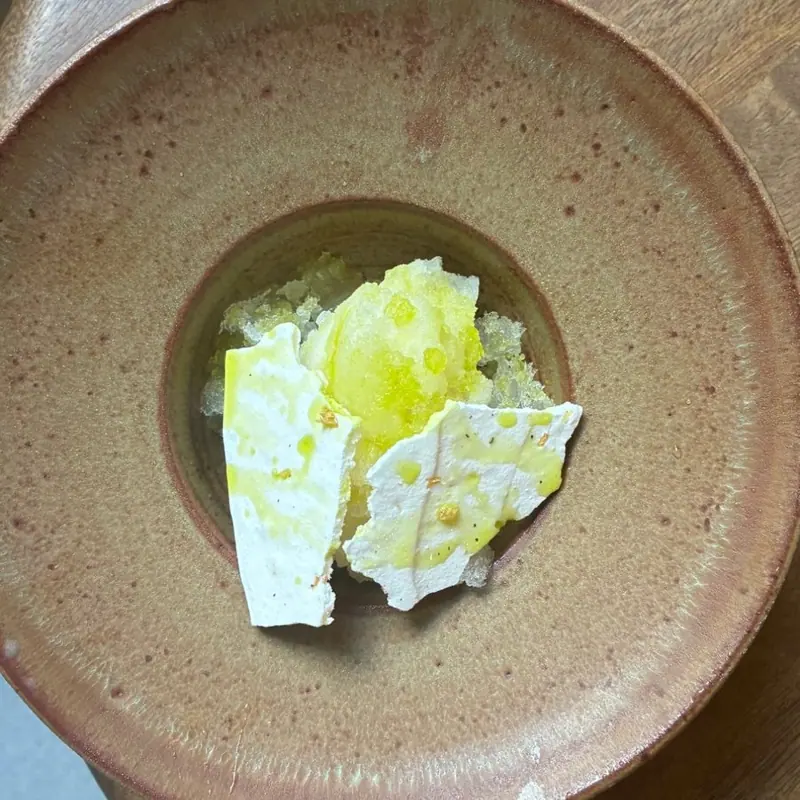 White shards and green leaves drizzled with oil in a stoneware bowl